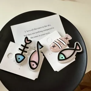 Detailed view of four colorful acrylic fish and fishbone shaped hair duckbill clips.