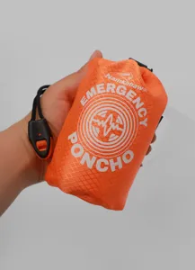 Detalle de poncho de emergencia con bolsa de almacenamiento naranja compacta y silbato.
