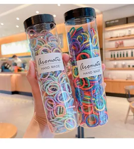 Colorful kids hair ties packed in two transparent bottles close up view