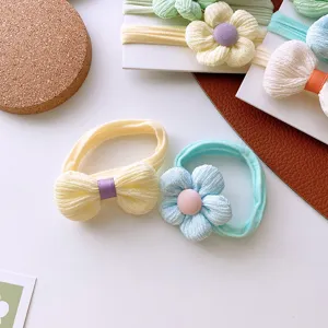 Detalle de coleteros de flores y lazos para niños en colores pastel suaves.