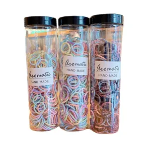 Set of three bottles containing colorful baby elastic hair ties with spiral design patterns