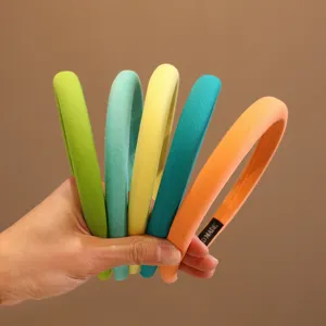 Set di cinque cerchietti minimalisti colorati rivestiti in tessuto per bambine in mano