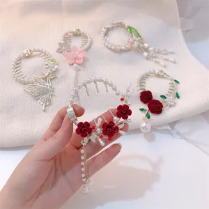 Close-up view of elegant circular hair clips featuring red roses and pearl tassels for bun styling