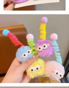 Mano que sostiene pinzas para el cabello de monstruos peludos de colores con ojos