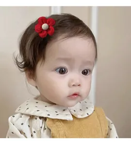 Close-up of a cute red fabric flower hair clip for babies on a little girl model