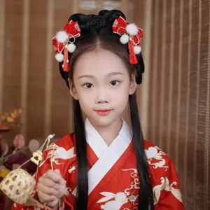 Detailed view of traditional Chinese red bow hair clips with tassels on a young girl