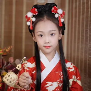 Detailed view of red Chinese New Year hair bows with tassels on a young girl.