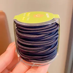 Close-up detail of bulk black elastic hair ties stored in a clear cylinder canister