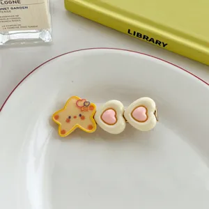 Macro view of a cute yellow star and pink heart duckbill hair clip on a white ceramic plate
