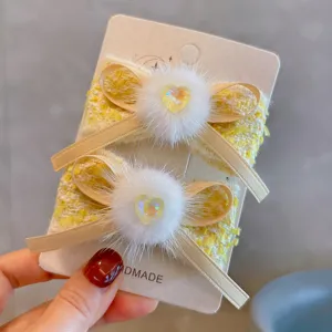 Detail showing yellow French style tweed hair clips with mink fur pom-poms and hearts