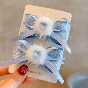 Close-up detail of blue tweed bow hair clips with white mink fur and heart gemstone.