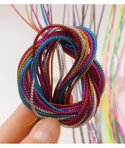 Macro dettaglio di cordoncini intrecciati metallici colorati per acconciature da bambina.