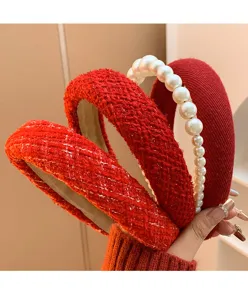 Detail of red headbands with tweed texture and pearl embellishments for festive outfits.