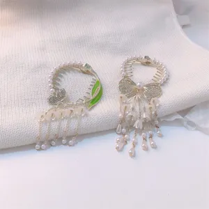 Detailed view of lily-of-the-valley hair clips with pearls and tassels on white knit