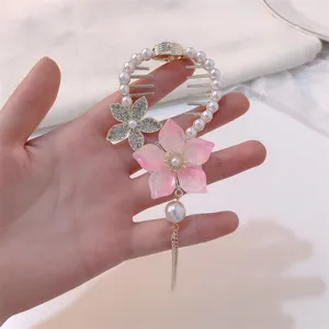 Detail shot of a pink flower hair claw clip with elegant dangling pearl tassel ornaments