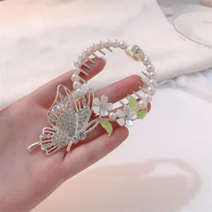 Close-up of elegant butterfly hair clip with pearls and floral details for buns.
