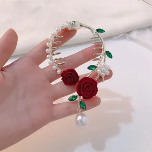Detailed view of elegant bun hair clip with red velvet roses and dangling pearl tassels