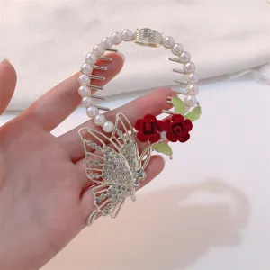 Close-up of an elegant butterfly and red rose bird nest hair claw clip with pearls and crystals