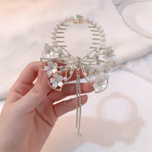 Detail view of white flower butterfly hair clip with long rhinestones tassel and pearls.
