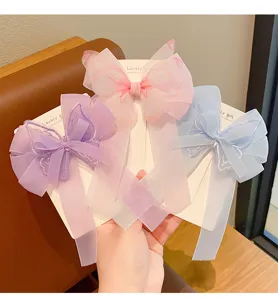 Vista detallada de tres elegantes clips de pelo de mariposa pastel con cintas largas