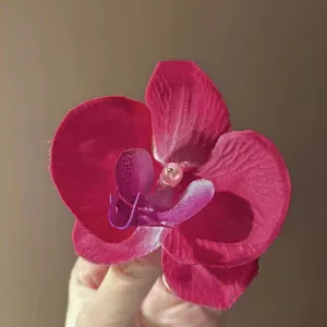 Close-up of a realistic fuchsia orchid flower hair clip with a delicate pink pearl center