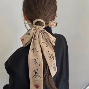Close-up of elegant ancient style hair ribbon with Chinese calligraphy and gold hairpin accessory.