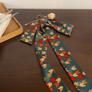 Retro dark green patterned hair ribbon with floral gold hairpin on a wooden surface