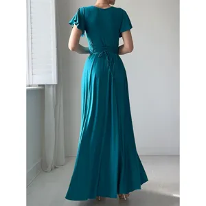 Détail de robe longue bleue sarcelle élégante avec manches volantées et ceinture nouée.