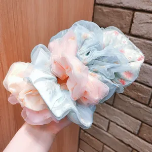 Close-up macro detail of layered floral chiffon scrunchies with soft ruffled texture