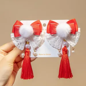 Detailed view of traditional Chinese red bow hair clips with tassels and pom-poms