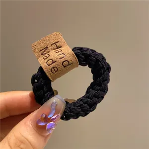 Dettaglio di un elastico per capelli nero intrecciato ad alta elasticità con etichetta.