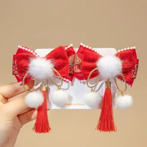 Close-up of festive red Chinese New Year hair clips with tassels and pom-poms on a card.