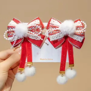 Detail view of Chinese New Year red hair clips with bow, pearls and white pom-poms.
