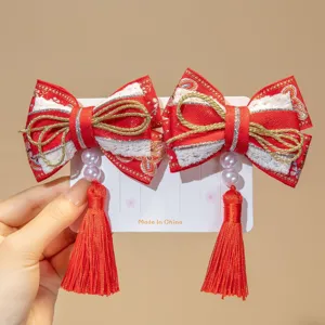 Detailed view of red Chinese style New Year bow hair clips with tassels for girls.