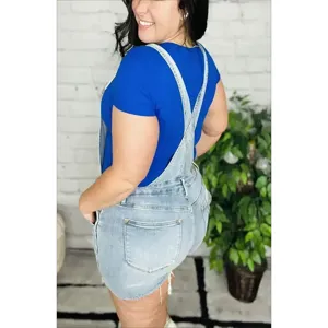 Femme short salopette en denim clair, short en jean avec bretelles vue de profil.