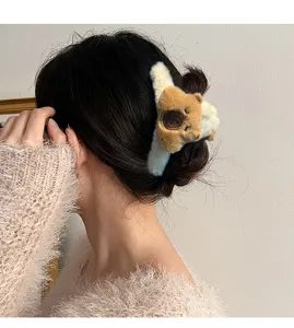 Close-up of a cute plush capybara hair claw clip worn on a woman's bun