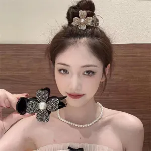 Close-up of sparkling rhinestone clover hair claw clip with pearl worn on a bun