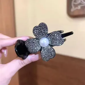 Macro detail of a sparkling rhinestone four-leaf clover hair clip with central pearl