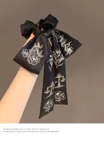 Elegante elastico in raso nero con ricamo floreale e lungo nastro fluente.