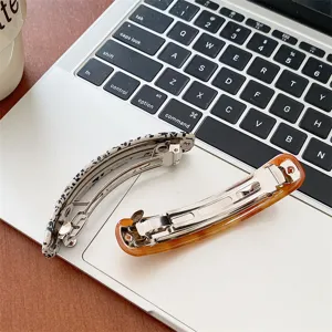 Close-up detail of elegant acetate hair barrettes featuring tortoiseshell and speckled patterns
