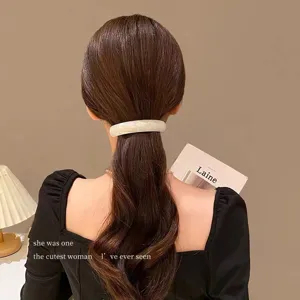 Close-up of elegant white acetate spring barrette worn on long wavy brown hair