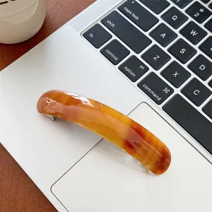 Macro view of elegant amber tortoiseshell acetate hair clip on a silver laptop