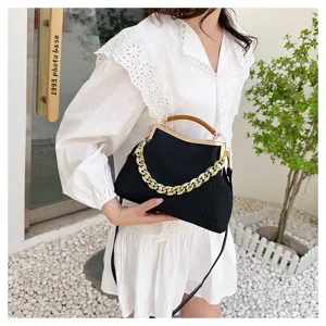 Detailed view of black striped handbag with large gold chain and wooden handle