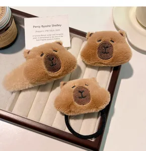 Close-up detail of soft brown plush capybara hair clips and elastic scrunchie set