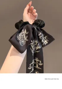Primo piano di elegante elastico in raso nero con nastri a fiocco floreali