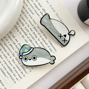 Detailed view of two cute Sacabambaspis acrylic hair clips placed on an open book