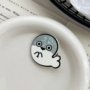Close-up of cute Sacabambaspis cartoon fish hair clip with grey marble texture