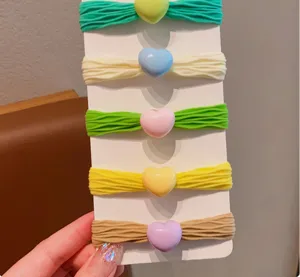 Dettaglio di elastici per capelli colorati in spugna con perline a cuore su carta bianca