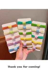 Dettaglio di elastici colorati per bambini con ciondoli a cuore e stella su cartoncini.