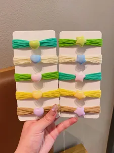 Dettaglio di elastici per capelli color pastello con ciondoli a cuore e a stella